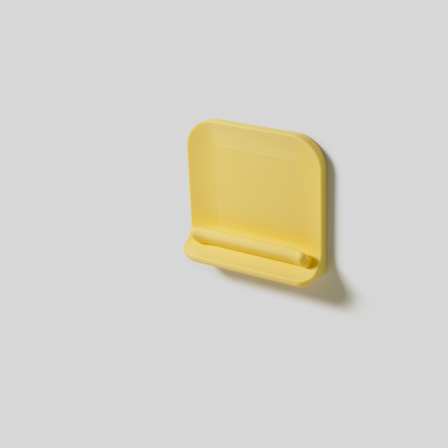 Yellow wall-mount with adhisive on a light gray background
