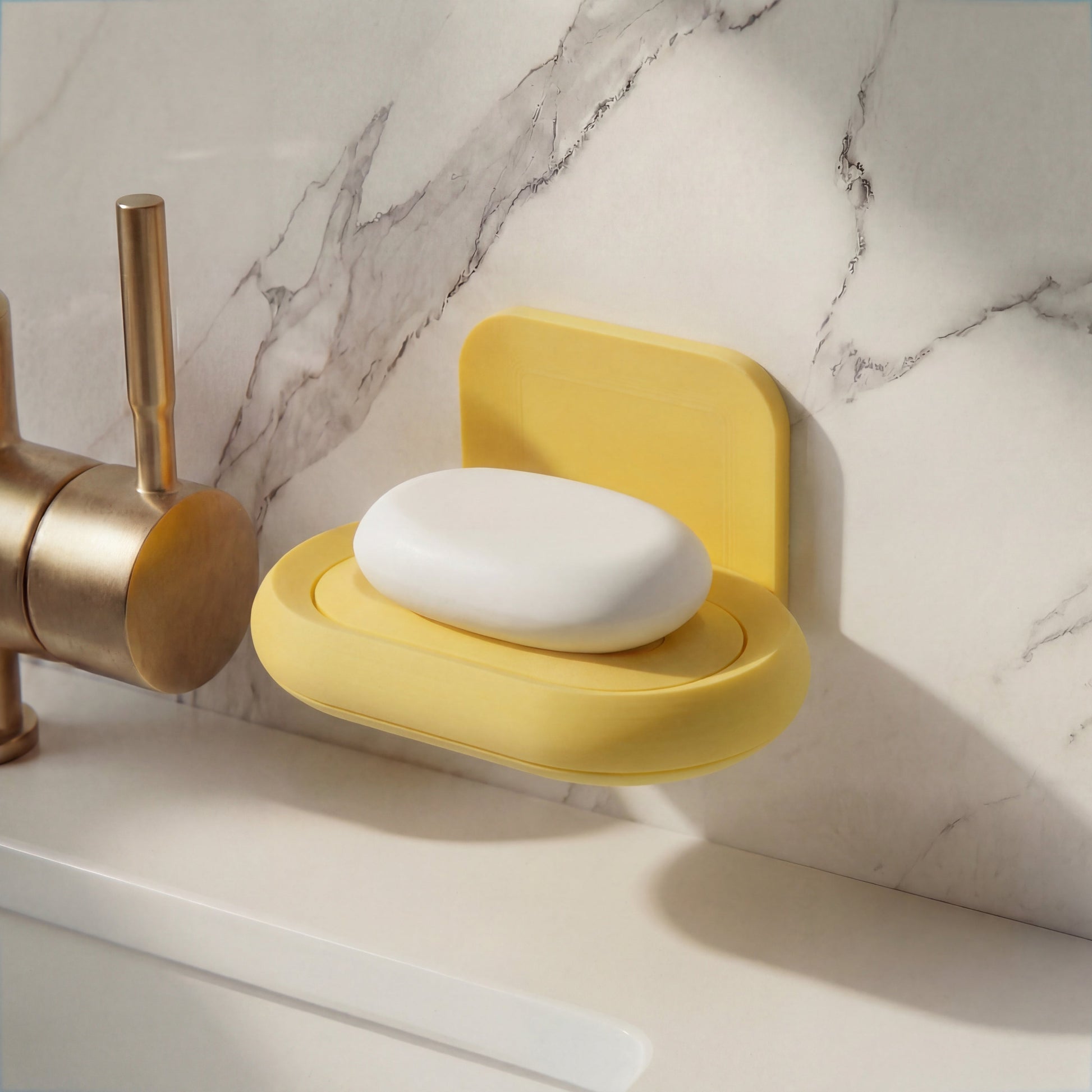 Yellow soap dish with a bar of soap on a marble countertop