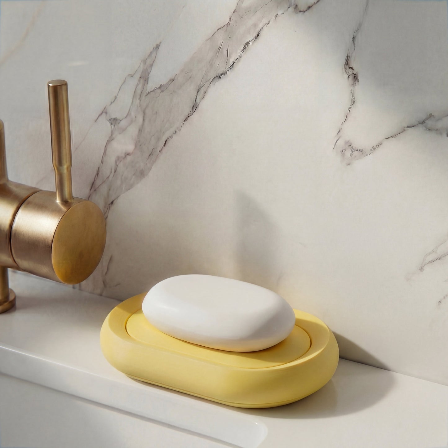 Yellow soap holder with a bar of soap on a marble countertop