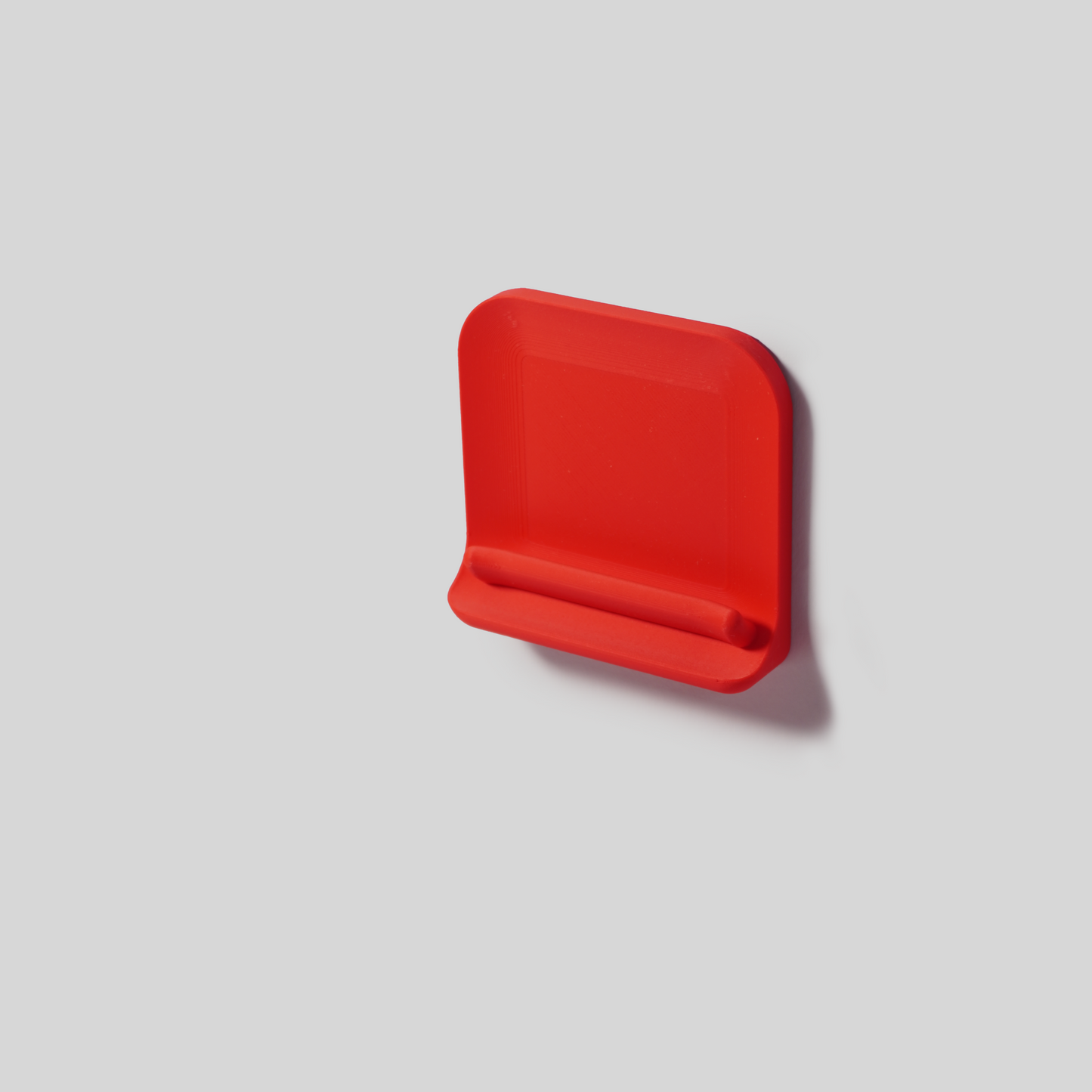 Red rectangular wall mount with adhisive on a light gray background