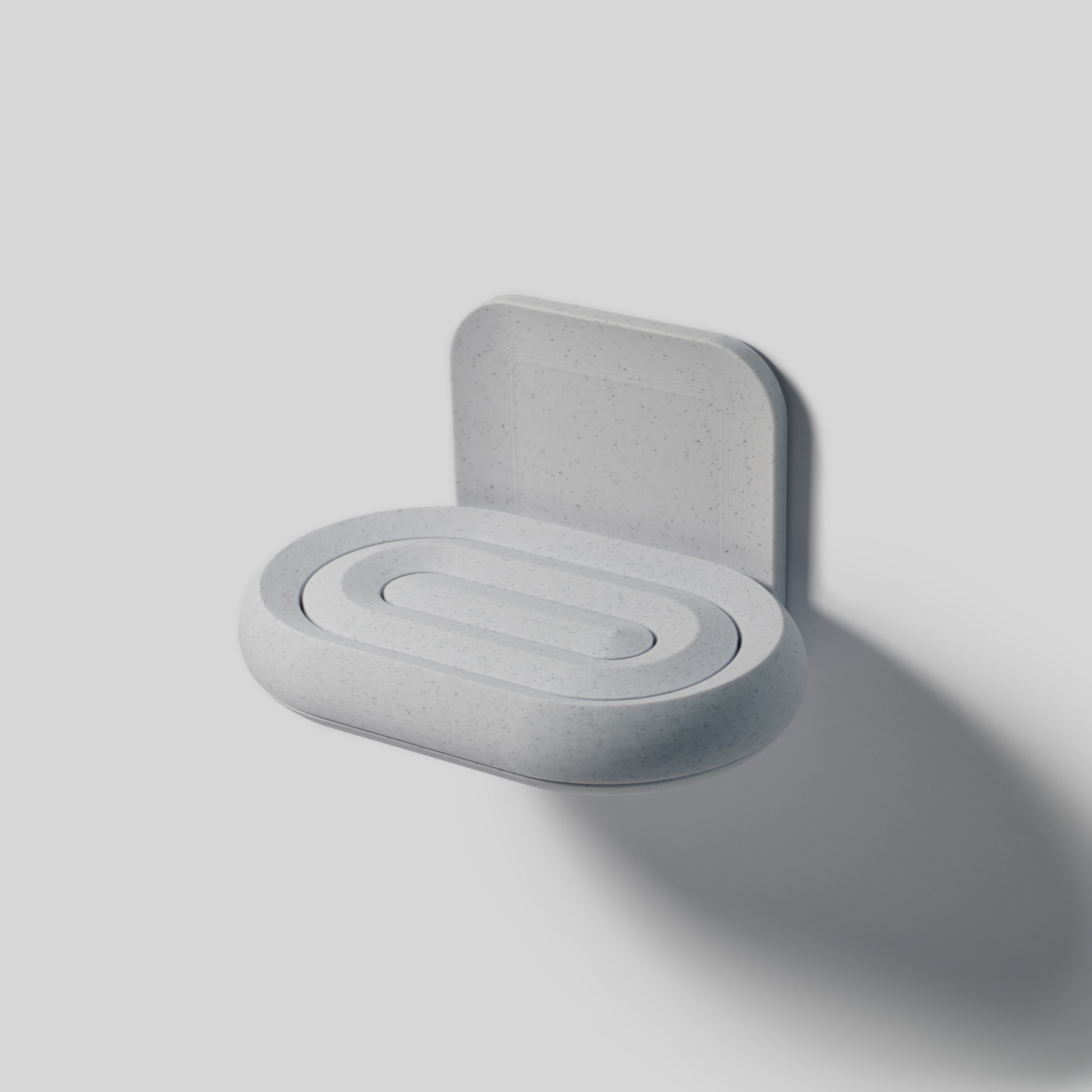 Gray wall-mounted soap holder with a round base on a light gray background