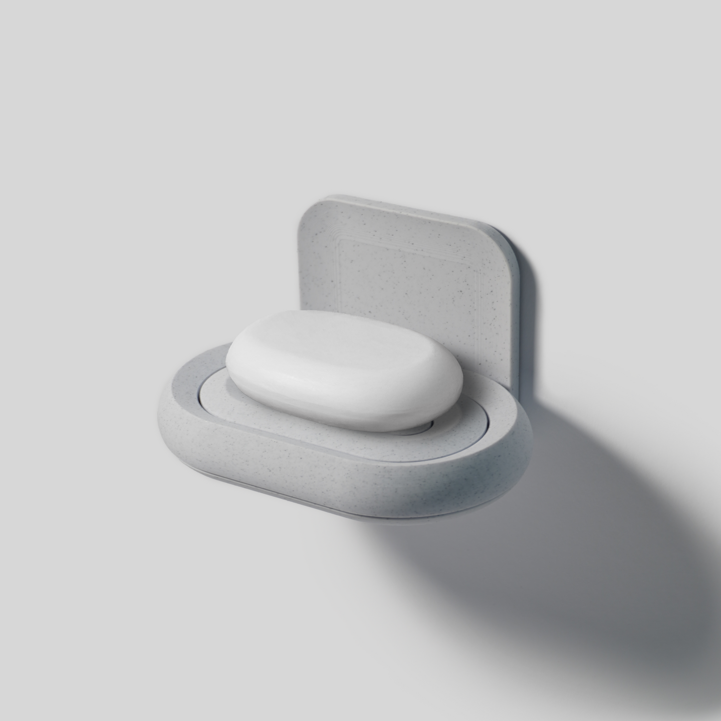 Wall-mounted gray soap holder with a white soap on a light gray background