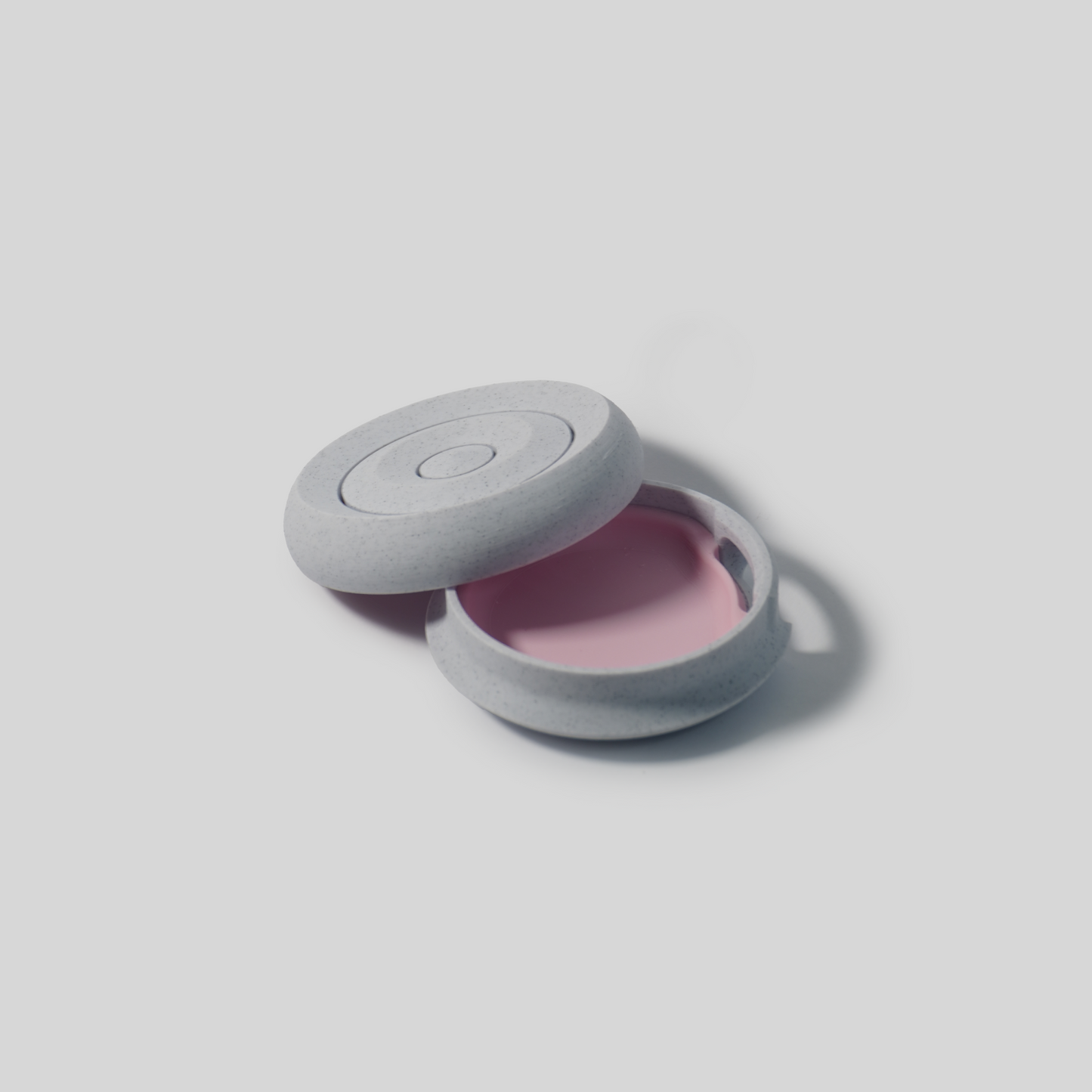 Round gray soap holder with a pink interior on a light gray background