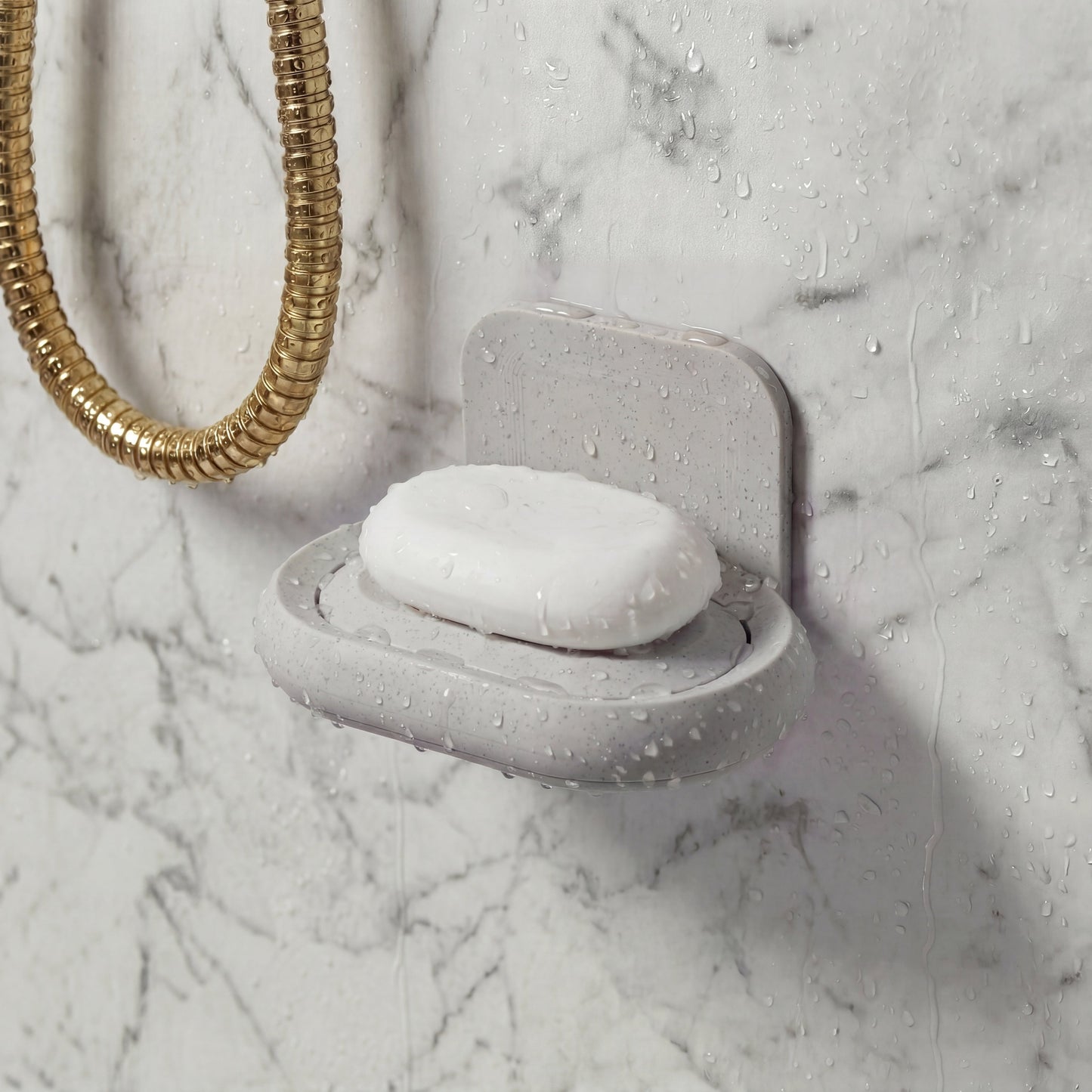 Gray soap dish with a bar of soap on a marble shower wall