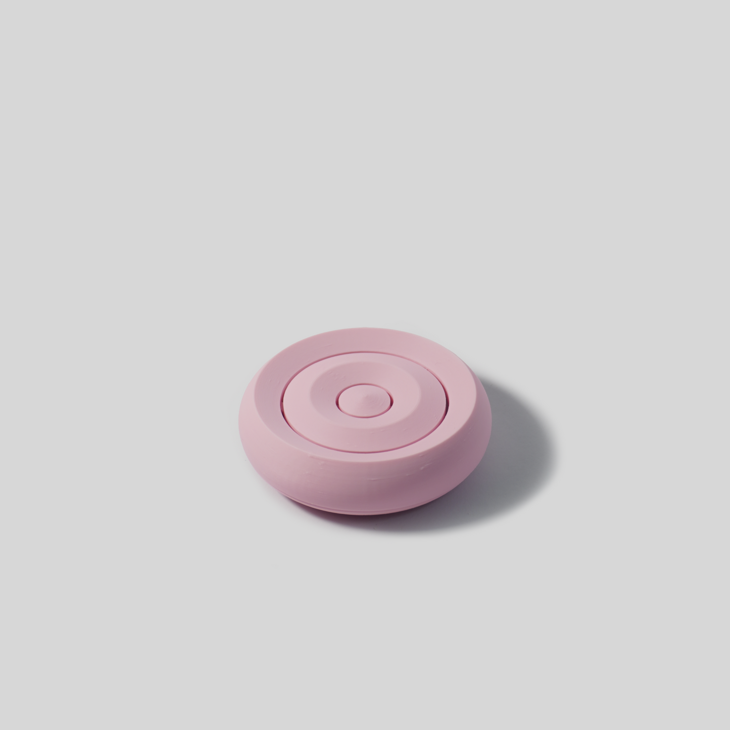 Pink round soap holder on a light gray background