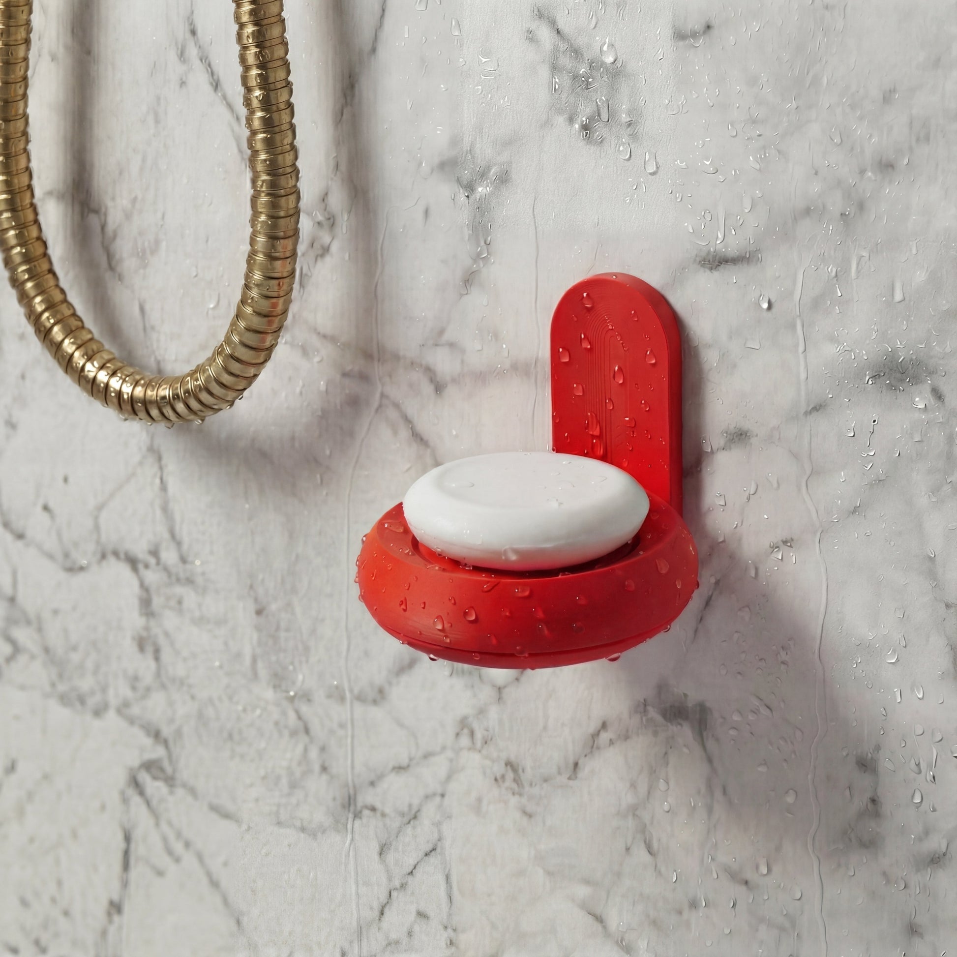 Red round soap holder with a white soap dish on a marble wall in the shower.