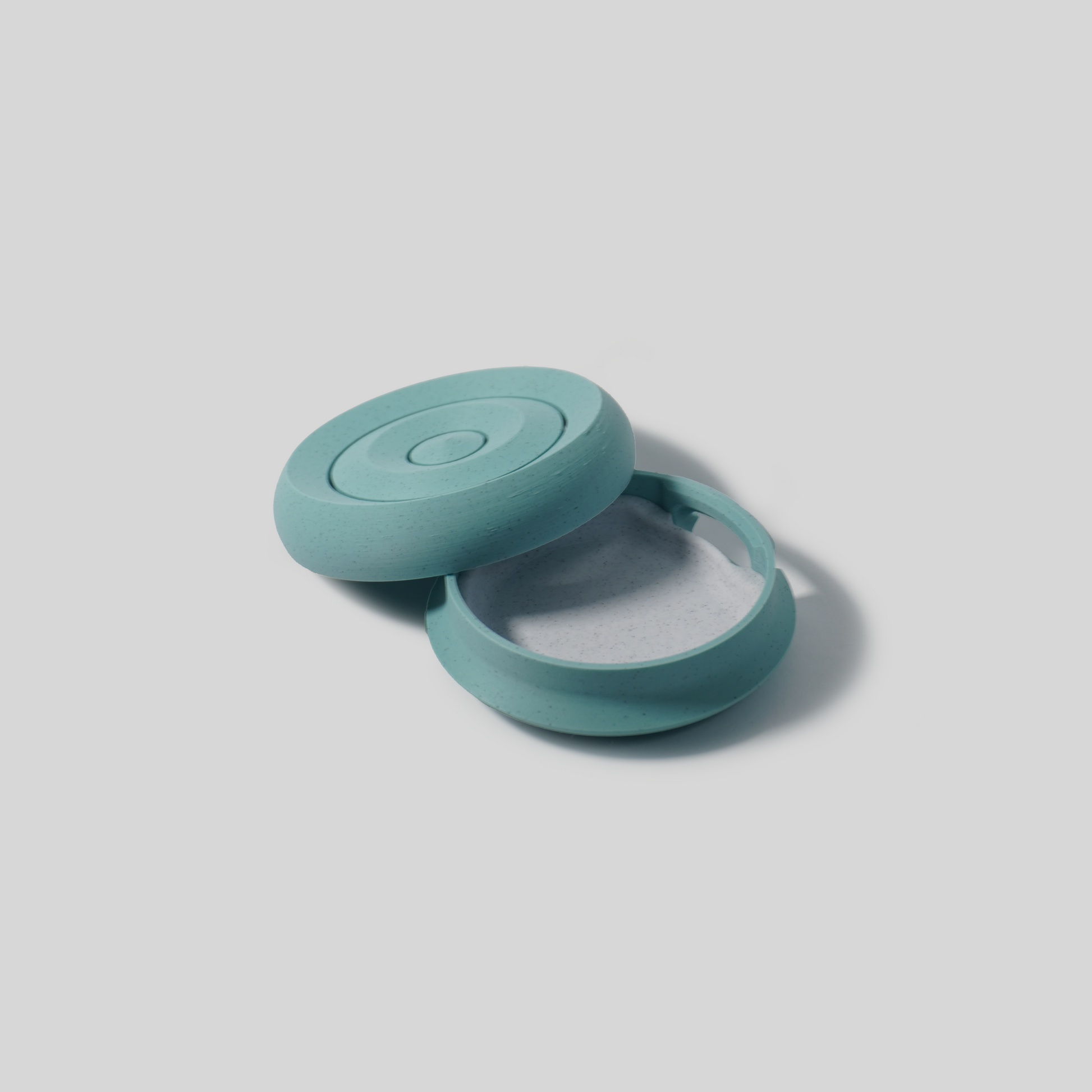 Teal-colored compact soap holder on a light gray background