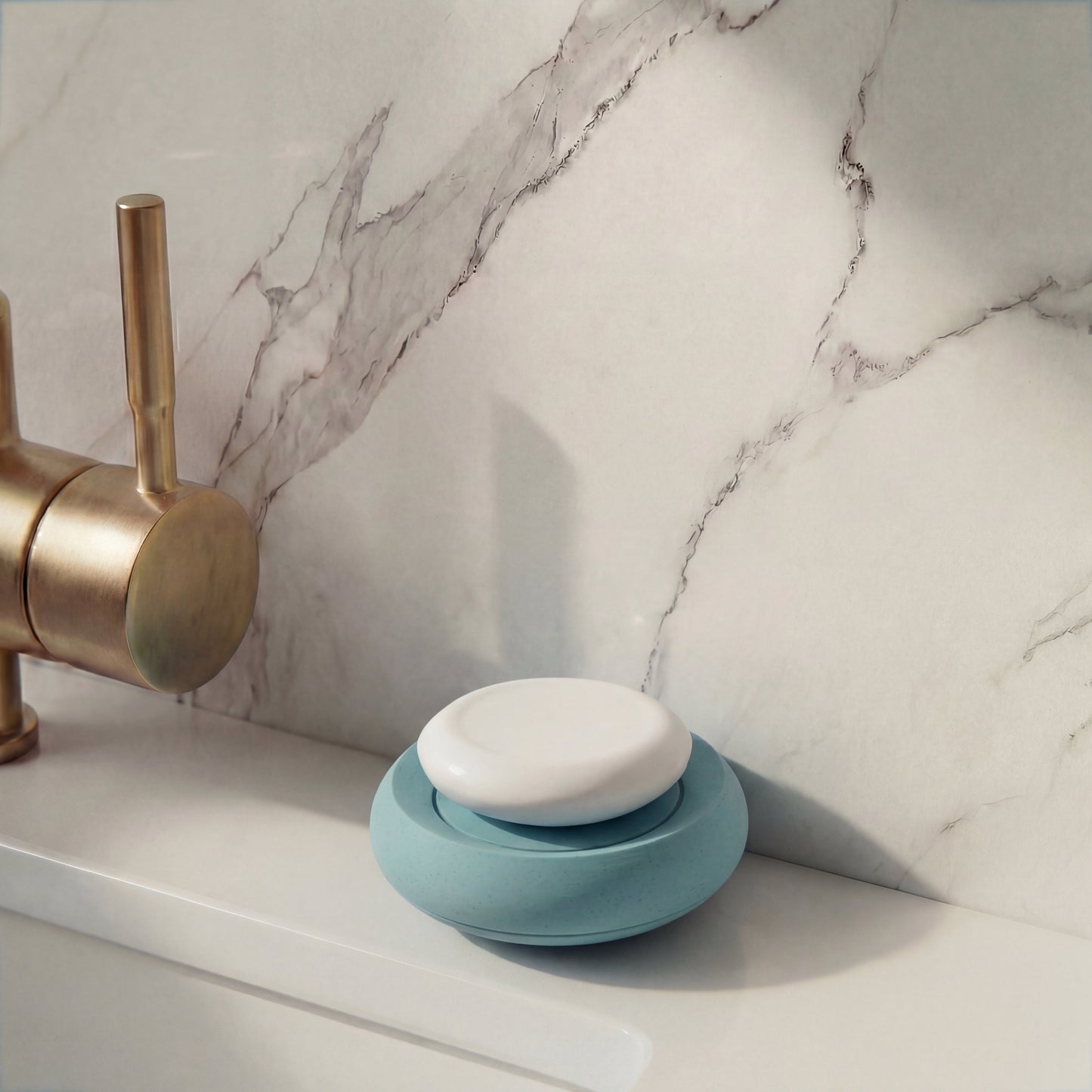 Blue and white soap dish on a marble bathroom counter with a brass faucet.