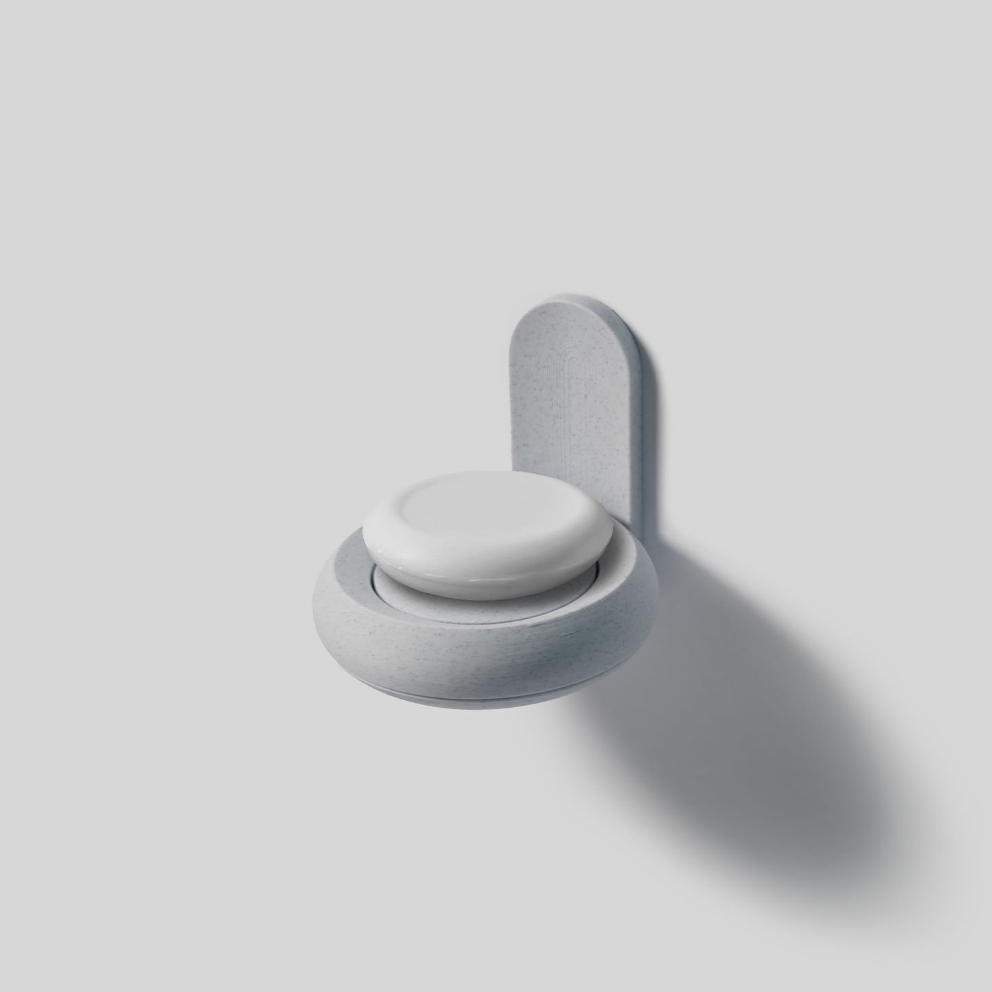 Gray wall-mounted soap holder with a round white soap on a light gray background