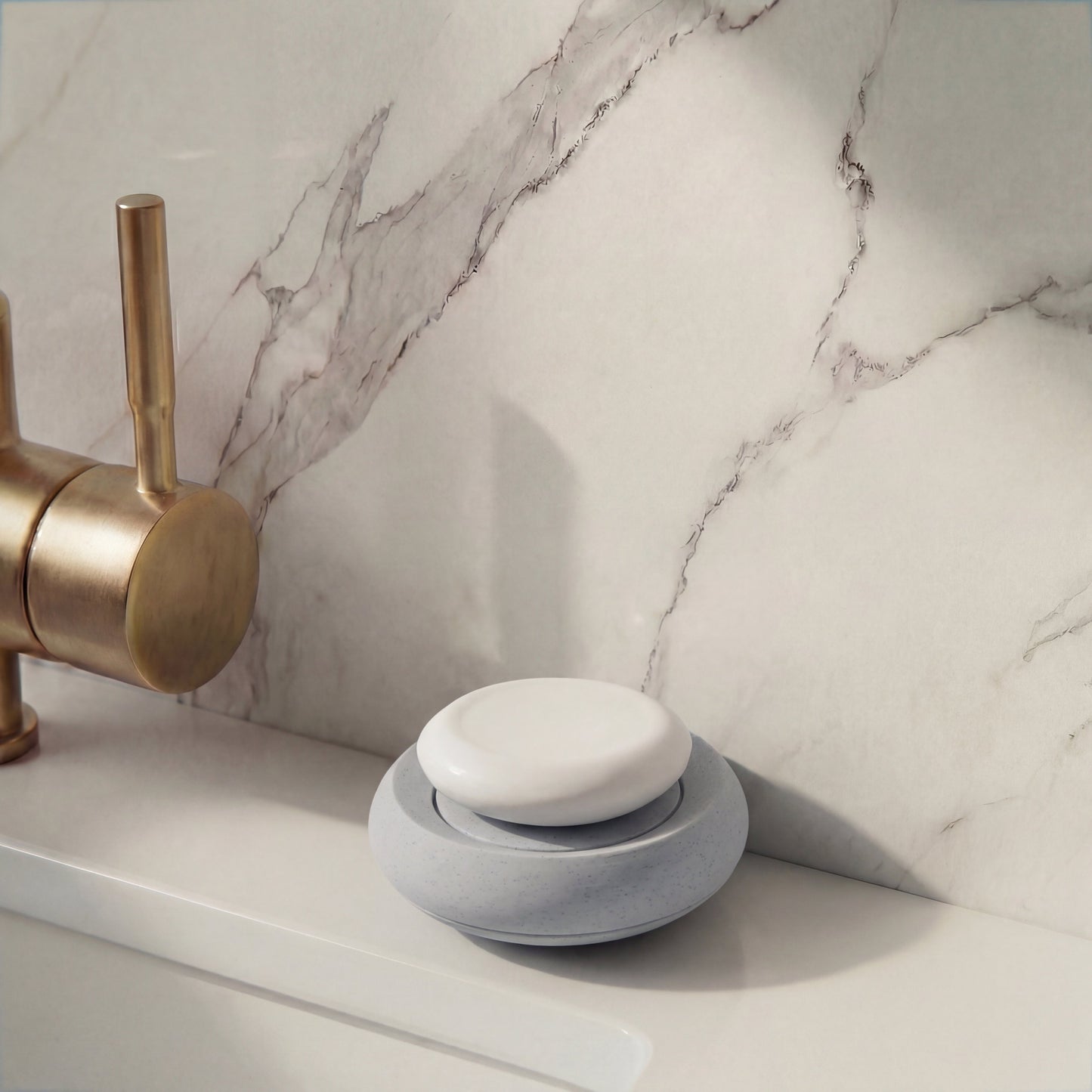 White soap holder  on a marble bathroom counter with brass faucet